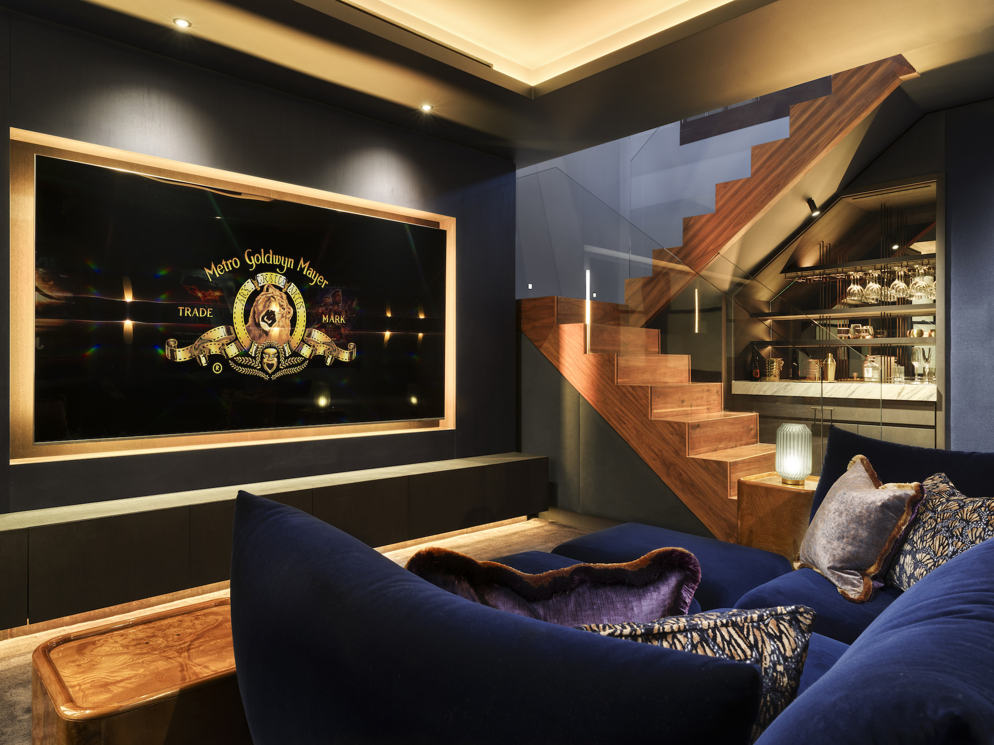 Chelsea Townhouse - LLI Design - Cinema Room - Overview 1 - upholstered walls and bespoke joinery framing 98 inch TV - orange DMX lighting