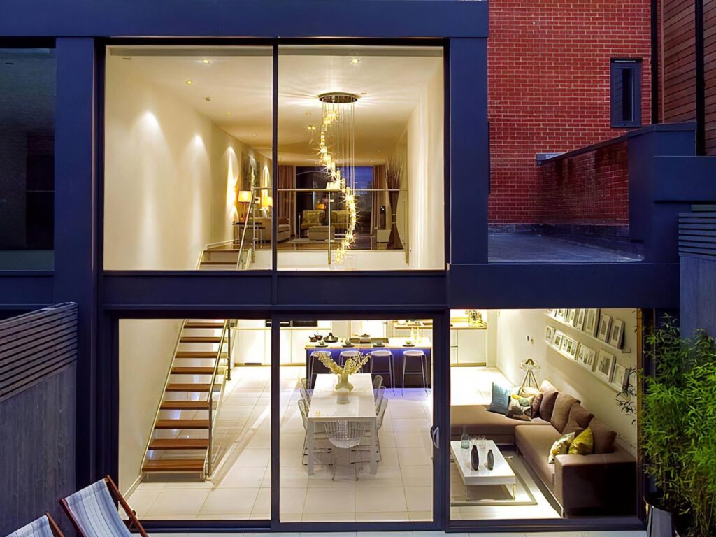 BG Tile Contemporary development, Crouch End: glazed rear of the house lit at dusk, showing two floors of living space